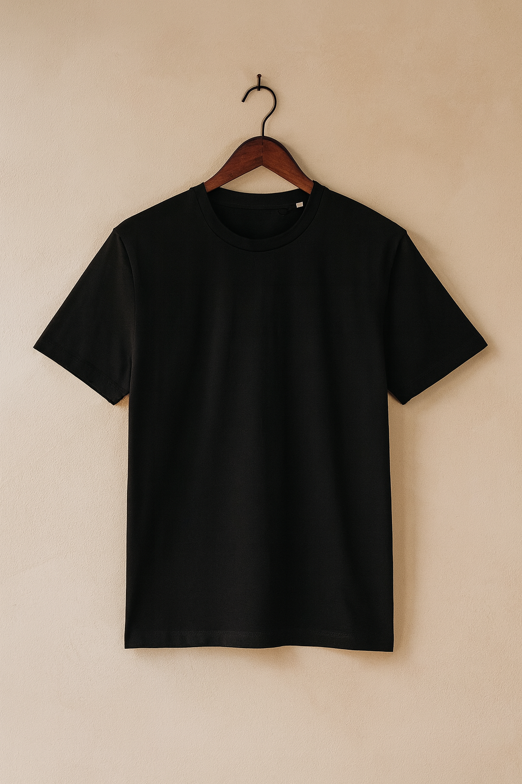 Black t-shirt on a hanger against a beige wall