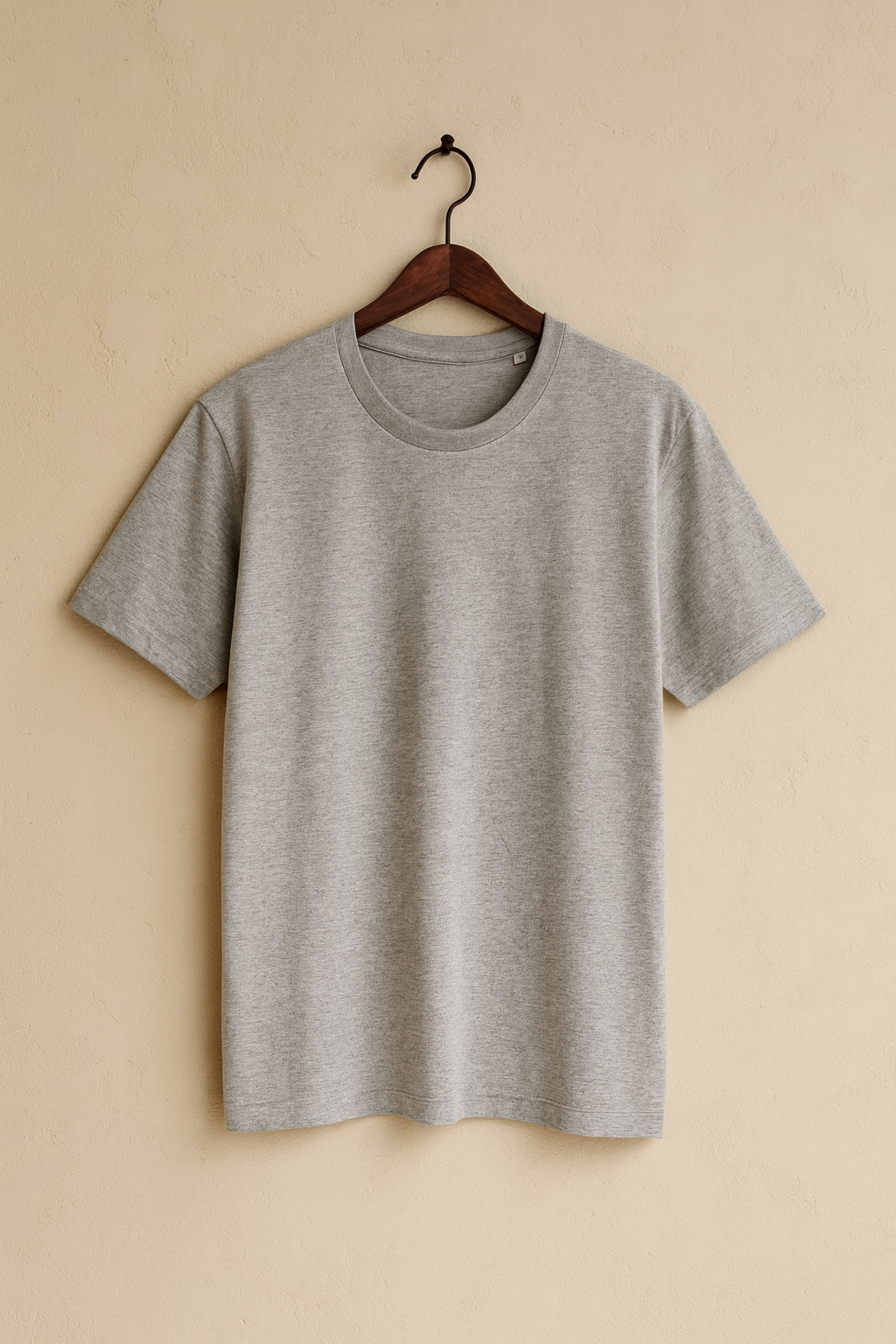 Gray t-shirt on a wooden hanger against a beige wall