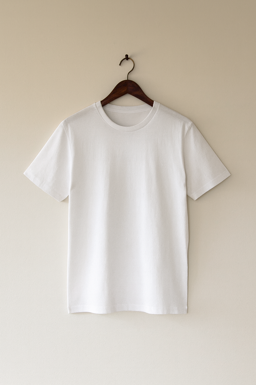 White t-shirt on a hanger against a beige wall