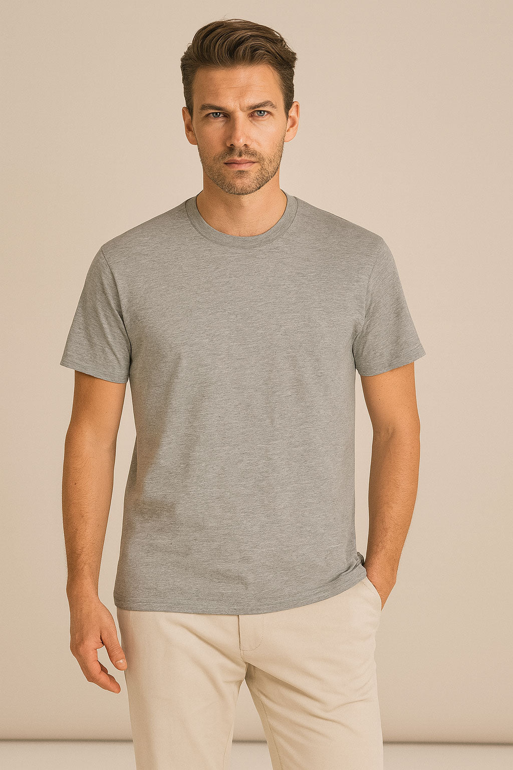 Man wearing a gray t-shirt and beige pants against a beige background