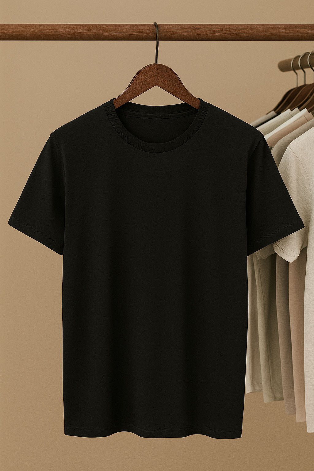 Black t-shirt on a hanger against a beige wall with other shirts in the background